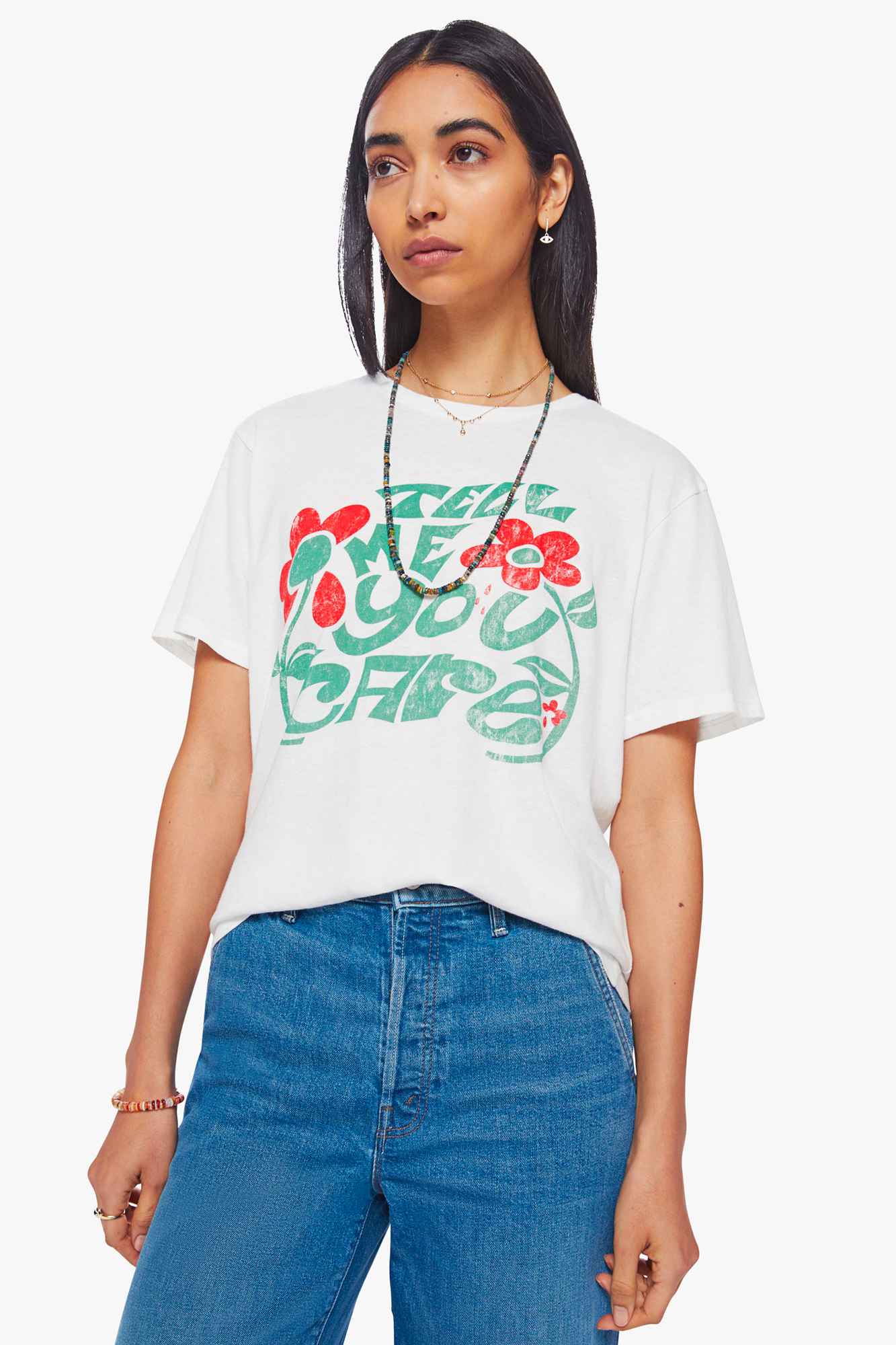 A crewneck tee with an oversized fit. Made from a recycled cotton blend, the white tee features a faded text graphic in green with red flowers on the front.