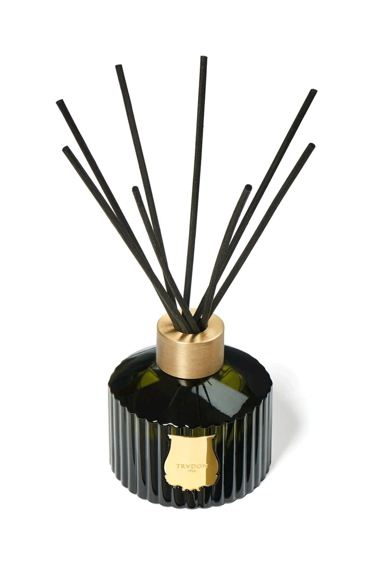 The Trudon Diffuser is handcrafted out of the same emblematic Trudon-green glass as the candles. The fluted container is adorned with a gold emblem. The Diffuser is topped with a 100% recyclable aluminum ring. Through it, you place 8 natural, black rattan sticks.