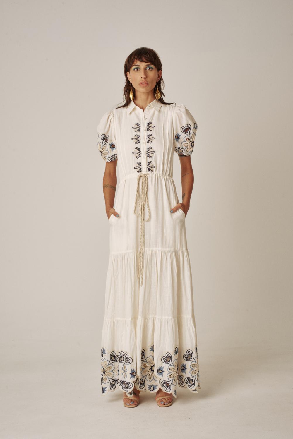 The Geo Dress from designer Carolina K in gardenia features hand cutout embroidery details in the top and bottom, draw string waist with rope belt, a collared top.